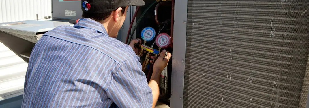 HVAC technician servicing a condenser unit in South Portland