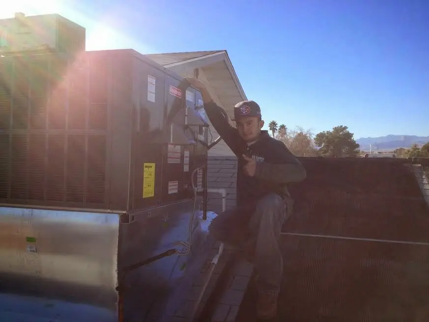 HVAC technician performing Air Duct Repair on a rooftop unit in South Portland